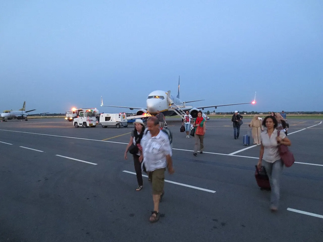 Pasażerowie idący do terminalu o zmierzchu