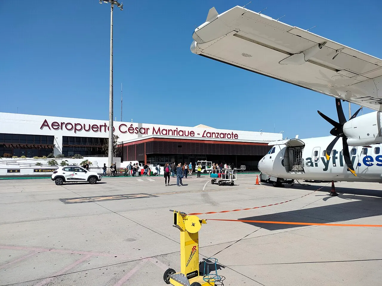 Fachada de la terminal vista desde la plataforma, junto a un avión turbohélice