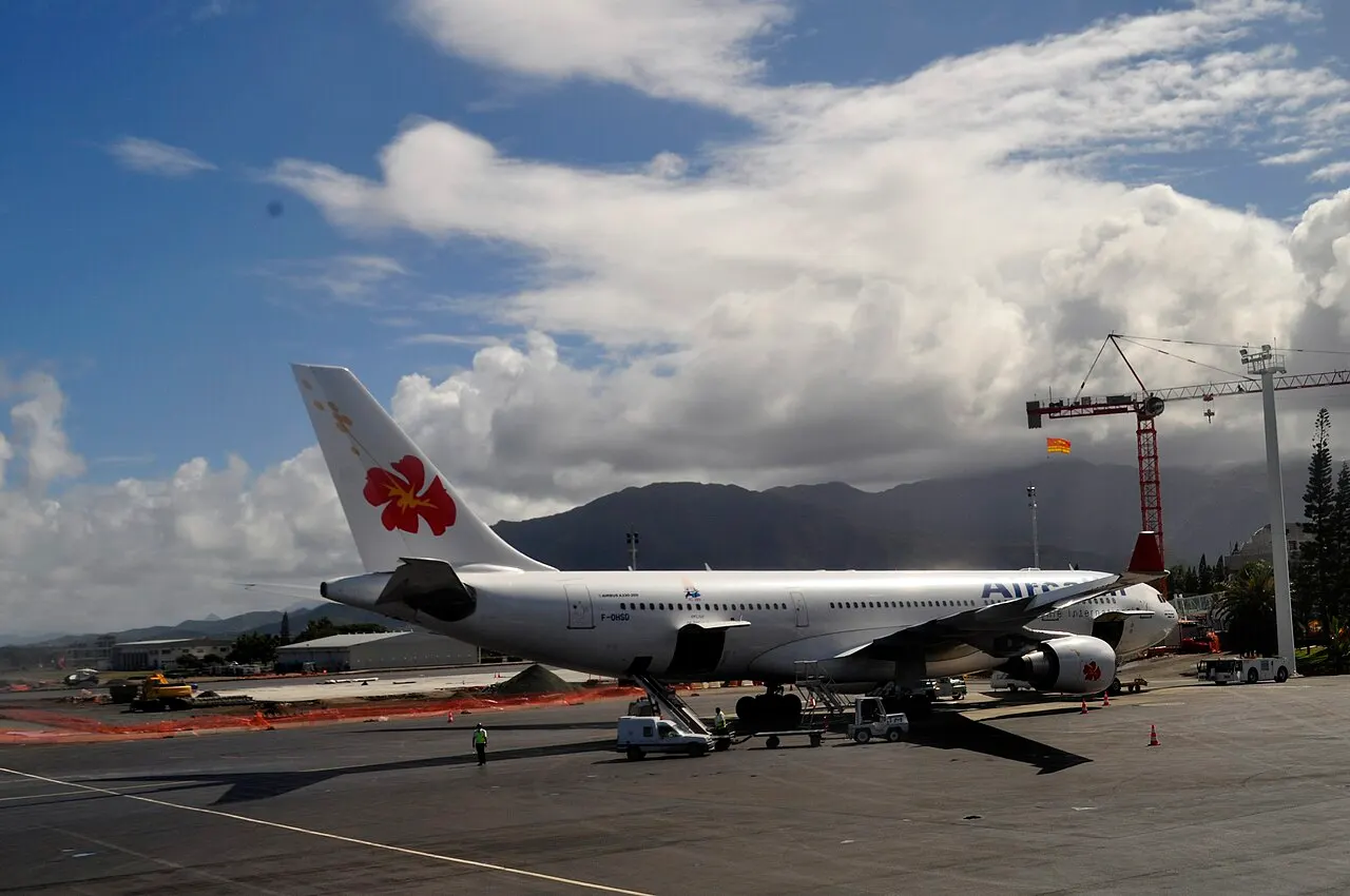 Een Airbus A330 van Aircalin op het platform, met de bergen op de achtergrond
