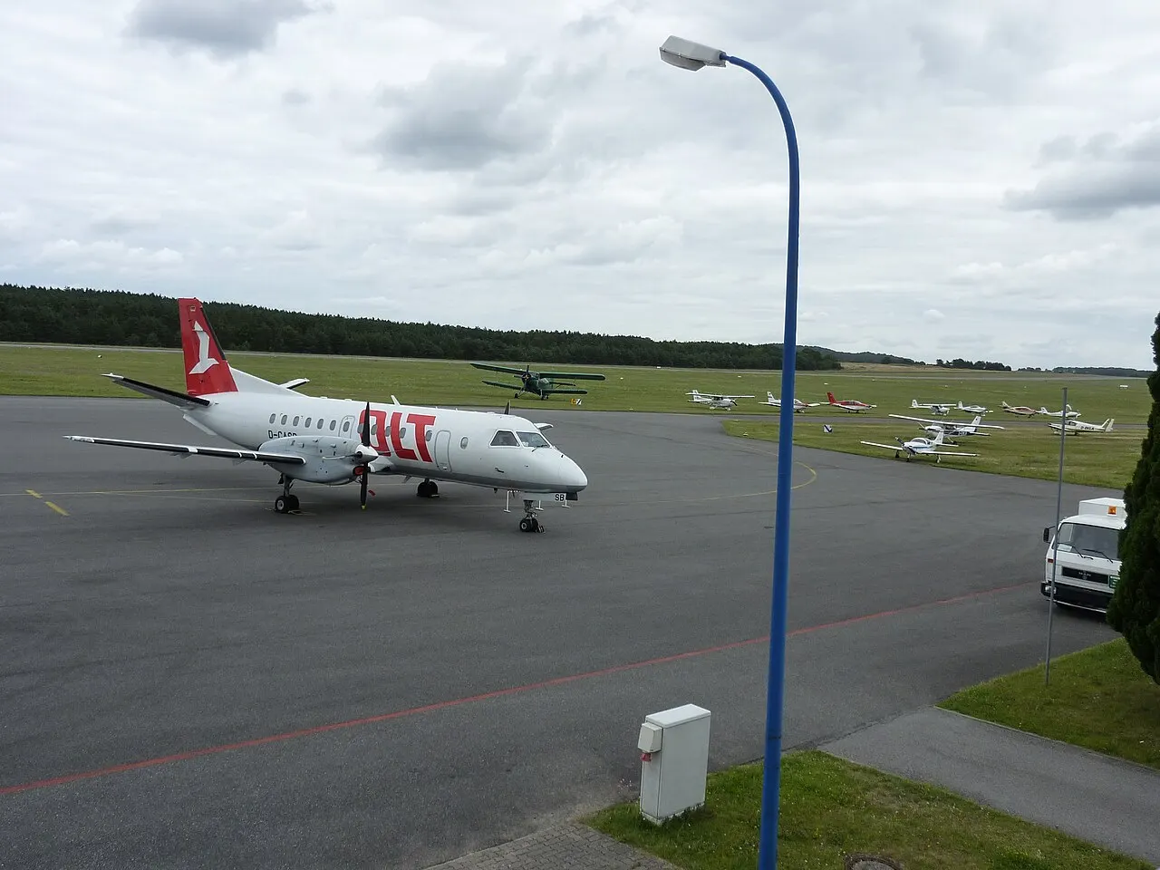 Een turbopropvliegtuig op het platform, met sportvliegtuigen op de achtergrond