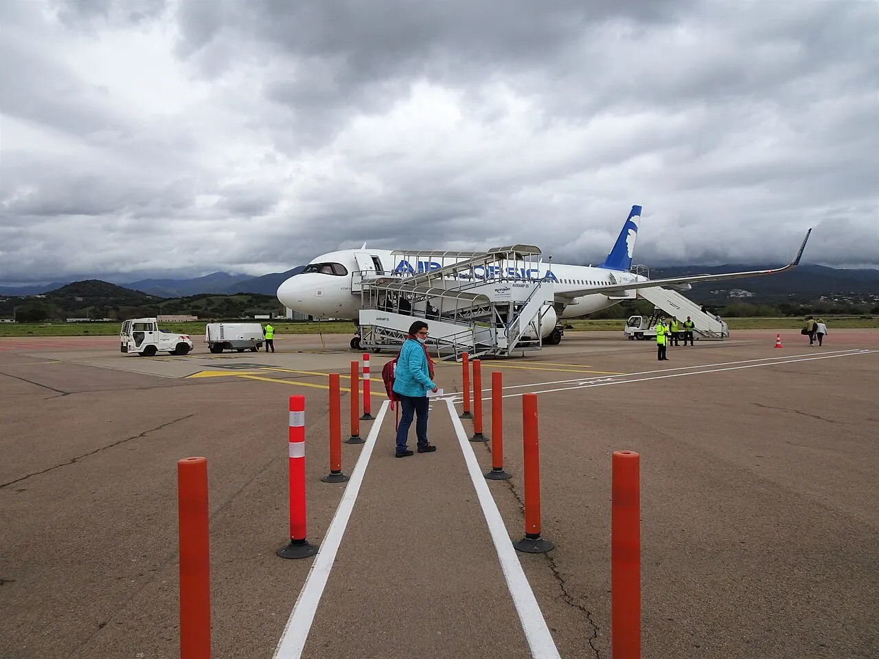 Passagiere gehen zu Fuß zu einem Flugzeug von Air Corsica