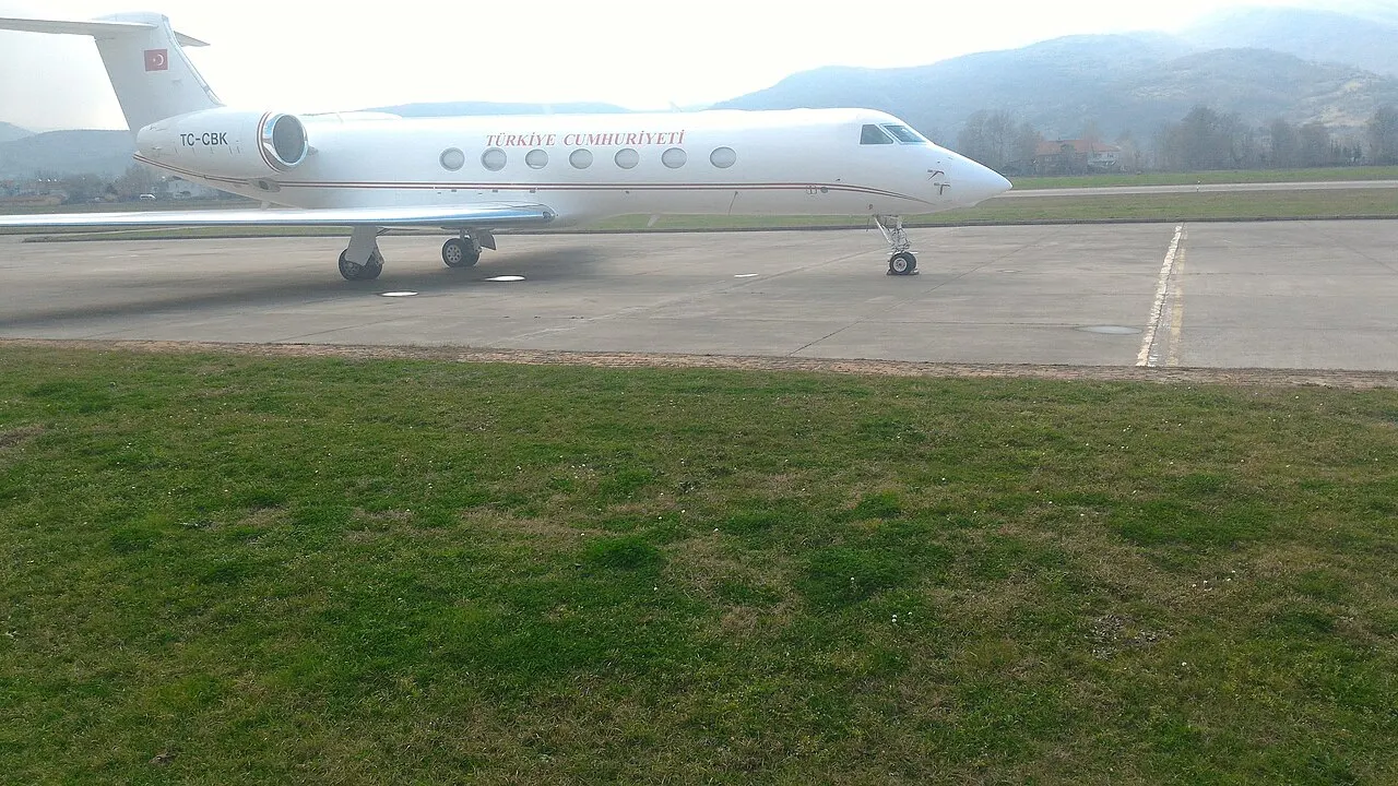 Ein Flugzeug auf dem Vorfeld, dahinter Hügel