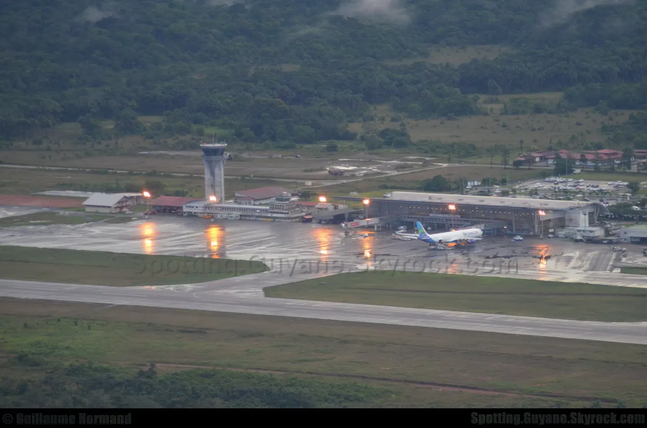 The terminal and control tower at nightfall, with the forest behind