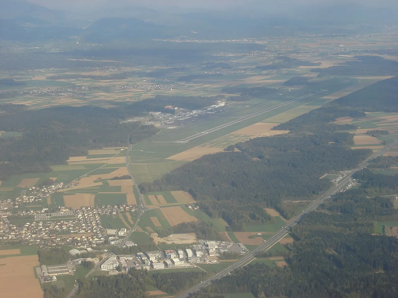 El aeropuerto y su pista vistos desde el aire, entre campos y bosques