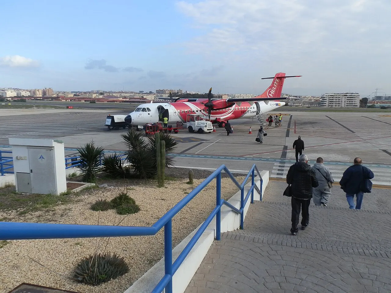 Passeggeri a piedi verso l'aereo, con Melilla sullo sfondo