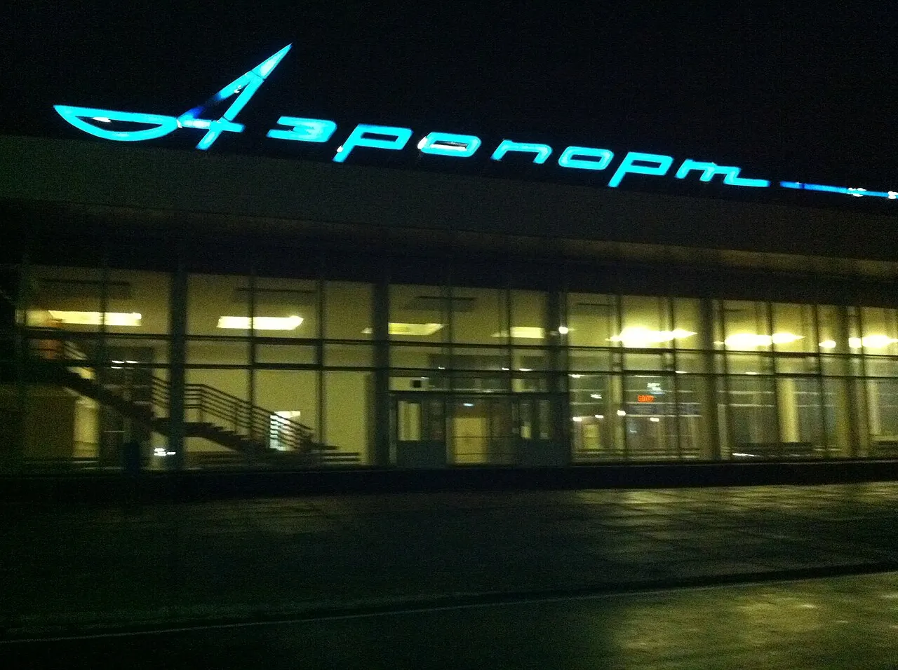 Het verlichte opschrift „Luchthaven” op de terminal in de nacht